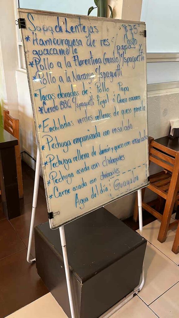 Menu written on a whiteboard by the entrance. Affordable restaurants in Mexico.
